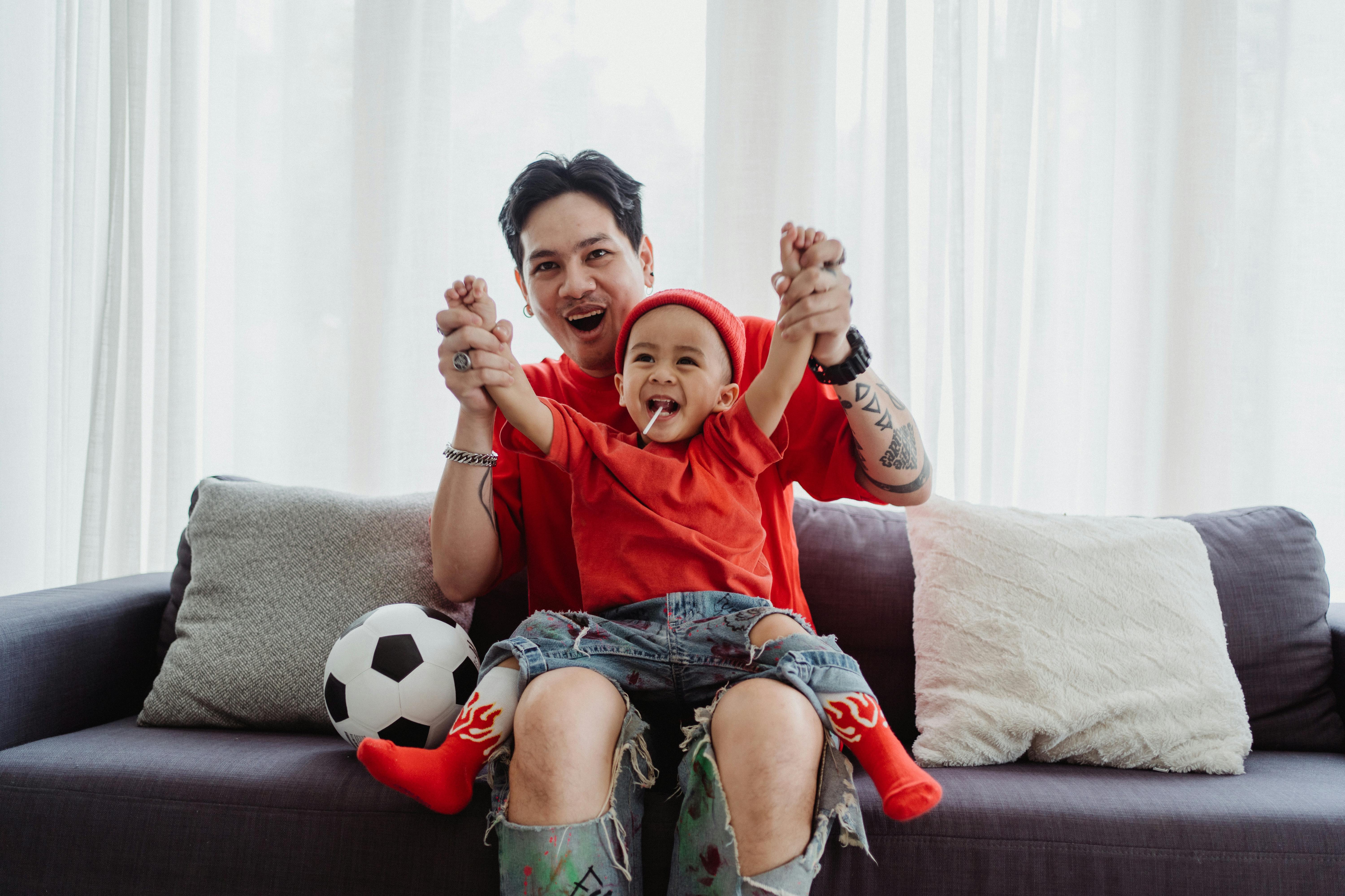 father and son cheering while watching a football match