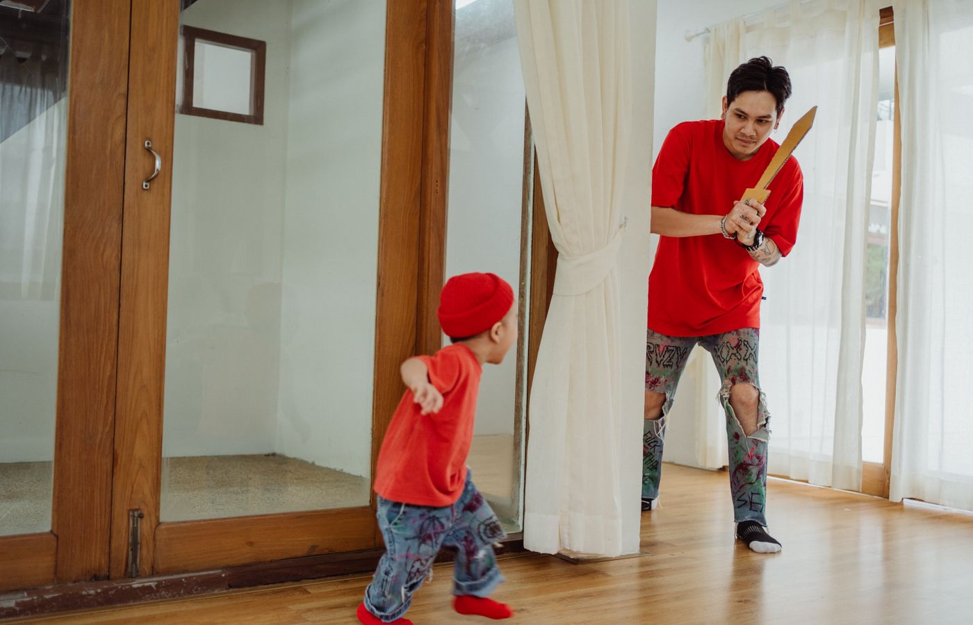 Father and son enjoy playful bonding time with a toy sword indoors.