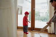 Boy in Red T-shirt and Blue Denim Shorts Standing Near Brown Wooden Framed Glass Door