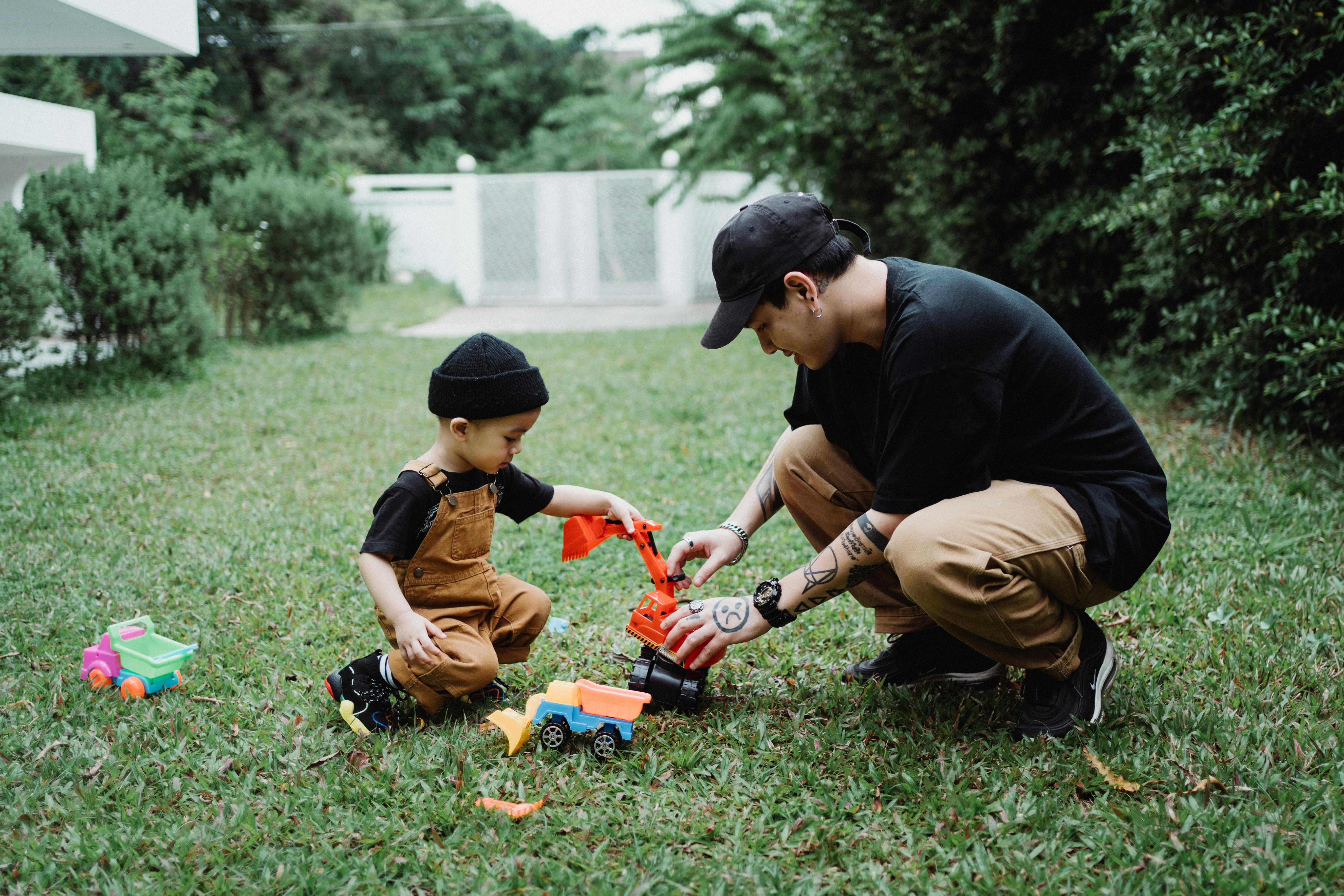 father and son playing with toy cars outside