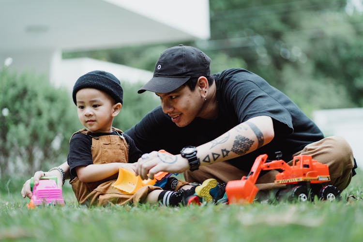 Father And Son Playing With Toy Cars Outside