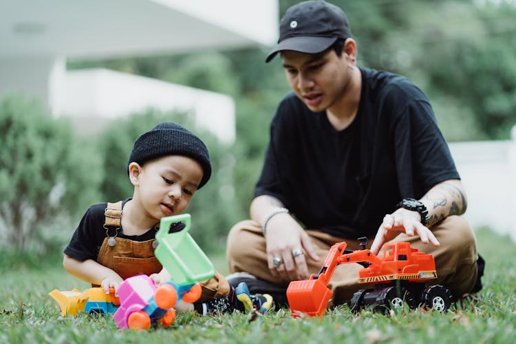 Father And Son Playing With Toy Cars Outside