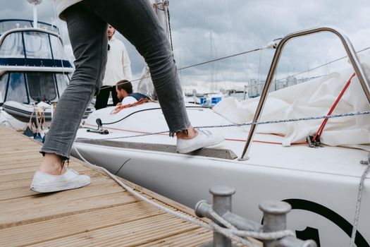 Close-up of a person boarding a yacht at a marina, showcasing nautical gear and casual attire.