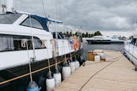 游艇停泊在码头上，在多云的天空中，索具可见，展示了航海生活方式