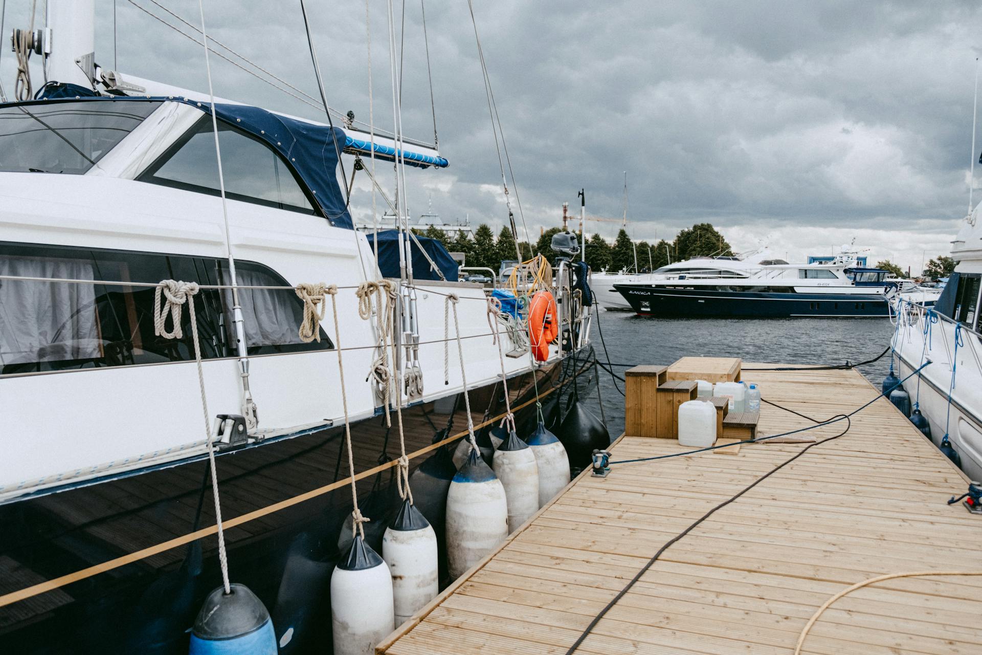 Yachts moored at a marina with rigging visible against a cloudy sky, showcasing nautical lifestyle.