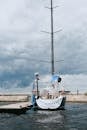 White and Blue Boat on Dock Under Cloudy Sky