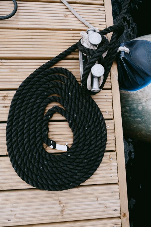 Free Detailed view of a coiled rope and winch on a wooden dock, perfect for nautical themes. Stock Photo