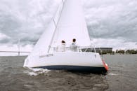 Man in White Shirt Sitting on White and Red Sailboat