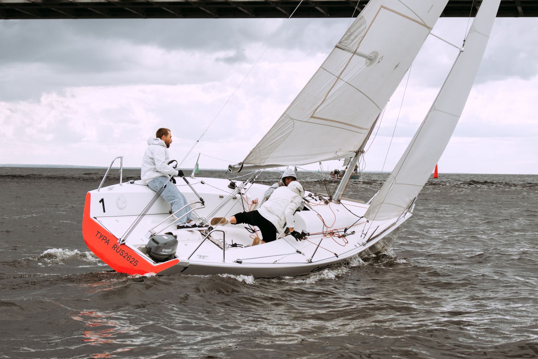 Crew sailing a yacht in a dynamic race, showcasing outdoor adventure and teamwork.