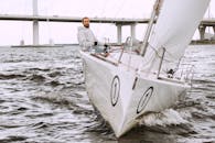 帆船手驾驶游艇，在醒目的桥下航行，体验快感