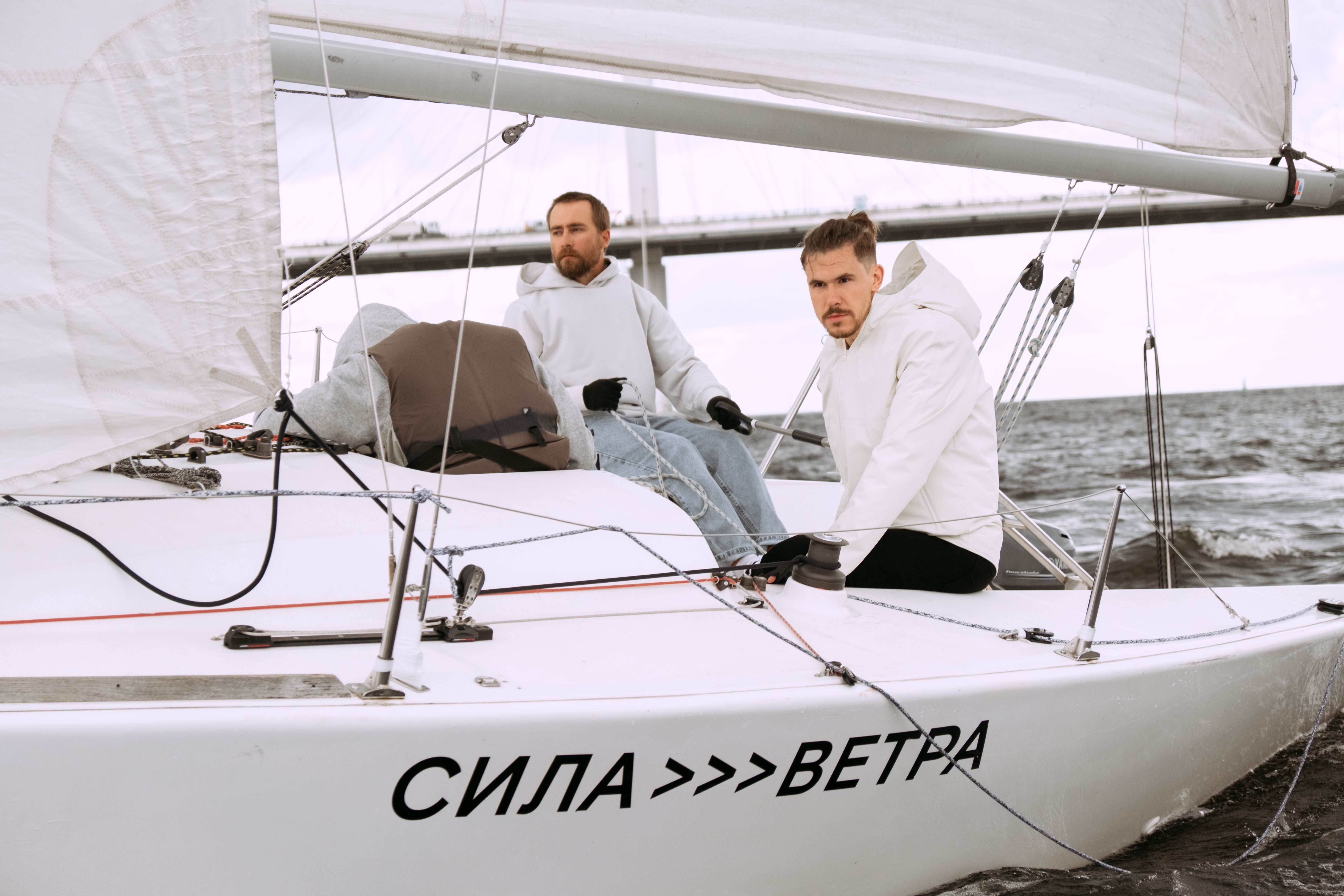 微风拂过的日子里，两名男子驾驶游艇，展示了团队合作与冒险精神