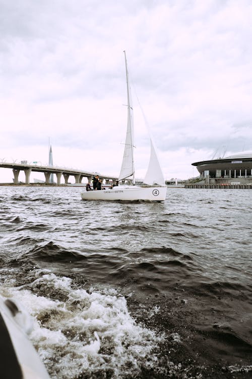 Perahu Putih Di Laut Dekat Jembatan Di Bawah Langit Berawan