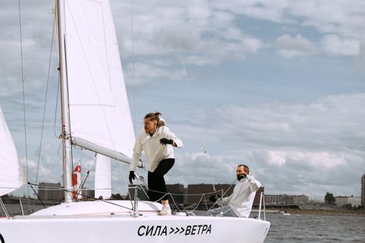 Two men sailing a yacht in open waters on a clear and sunny day.