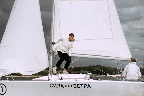 Man in White Shirt and Black Pants on White Boat