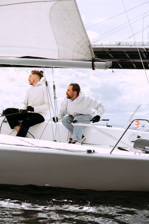 Man in White Dress Shirt and Black Pants Sitting on White Boat