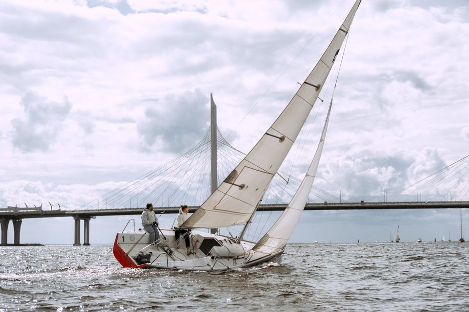 Best Private 6 Hour Fishing Charter in Nassau Review: Your Ultimate Guide to Deep Sea Adventure in the Bahamas Review 2026 - A sailboat with two people navigating the ocean beneath a large bridge on a cloudy day.