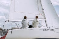 Man in White Dress Shirt and Black Pants Sitting on White Yacht