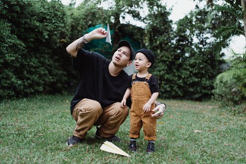 Free A father and child enjoying quality outdoor time in the garden with paper planes. Stock Photo