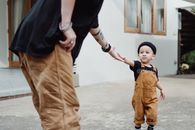 Boy in Black T-shirt and Brown Pants Standing on Gray Concrete Floor