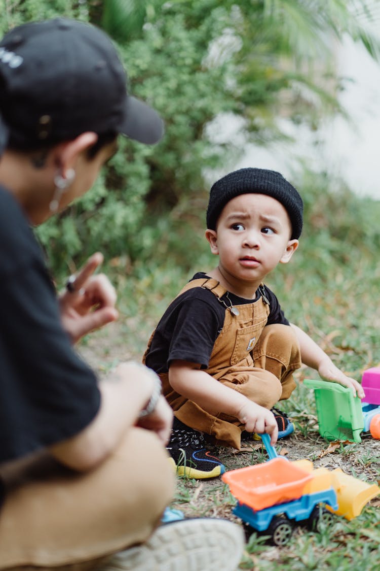 Man Explaining To Son While Playing With Toys Outdoors