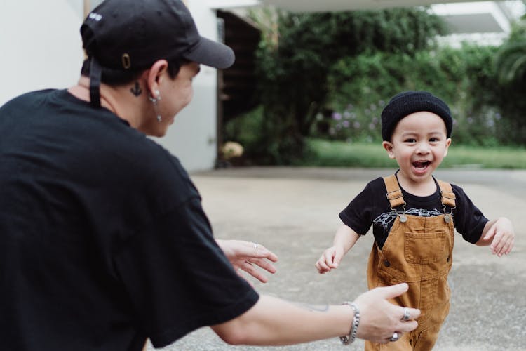 Boy In Dungarees And Black Hat Running To His Father