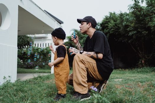 Father and Son Making Soap Bubbles in Patio