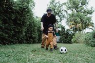 Father Playing Ball with Son on Grass