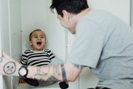 Man in Gray T-Shirt Entertaining Little Boy in Black and White Striped Shirt