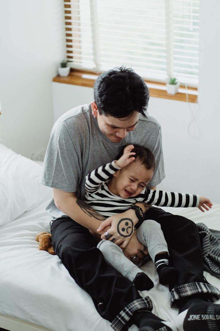 Little Boy In Striped Shirt Crying In Man's Hands