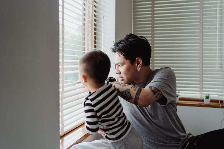 Father And Son Looking Out Through Window