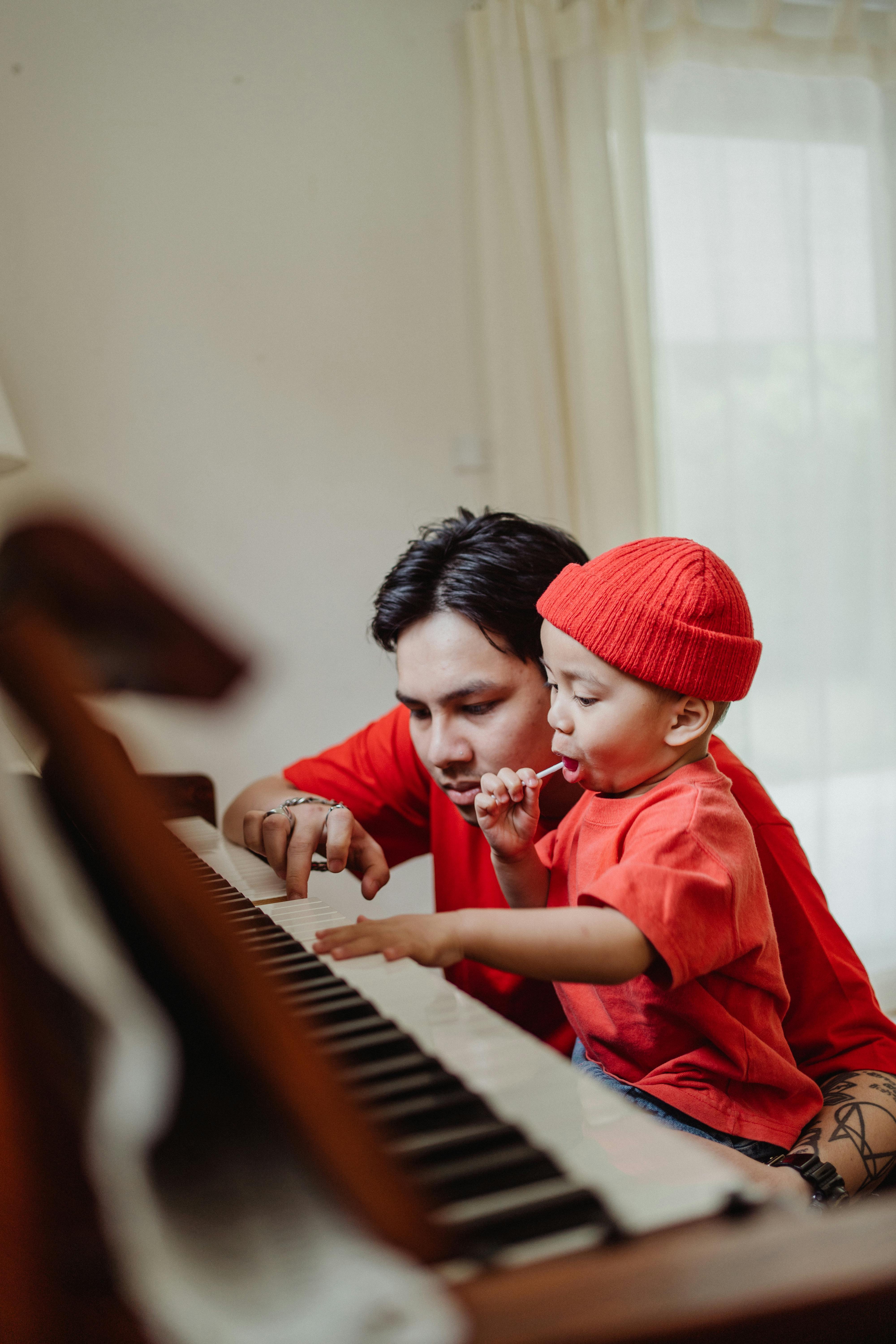father teaching playing piano to his son