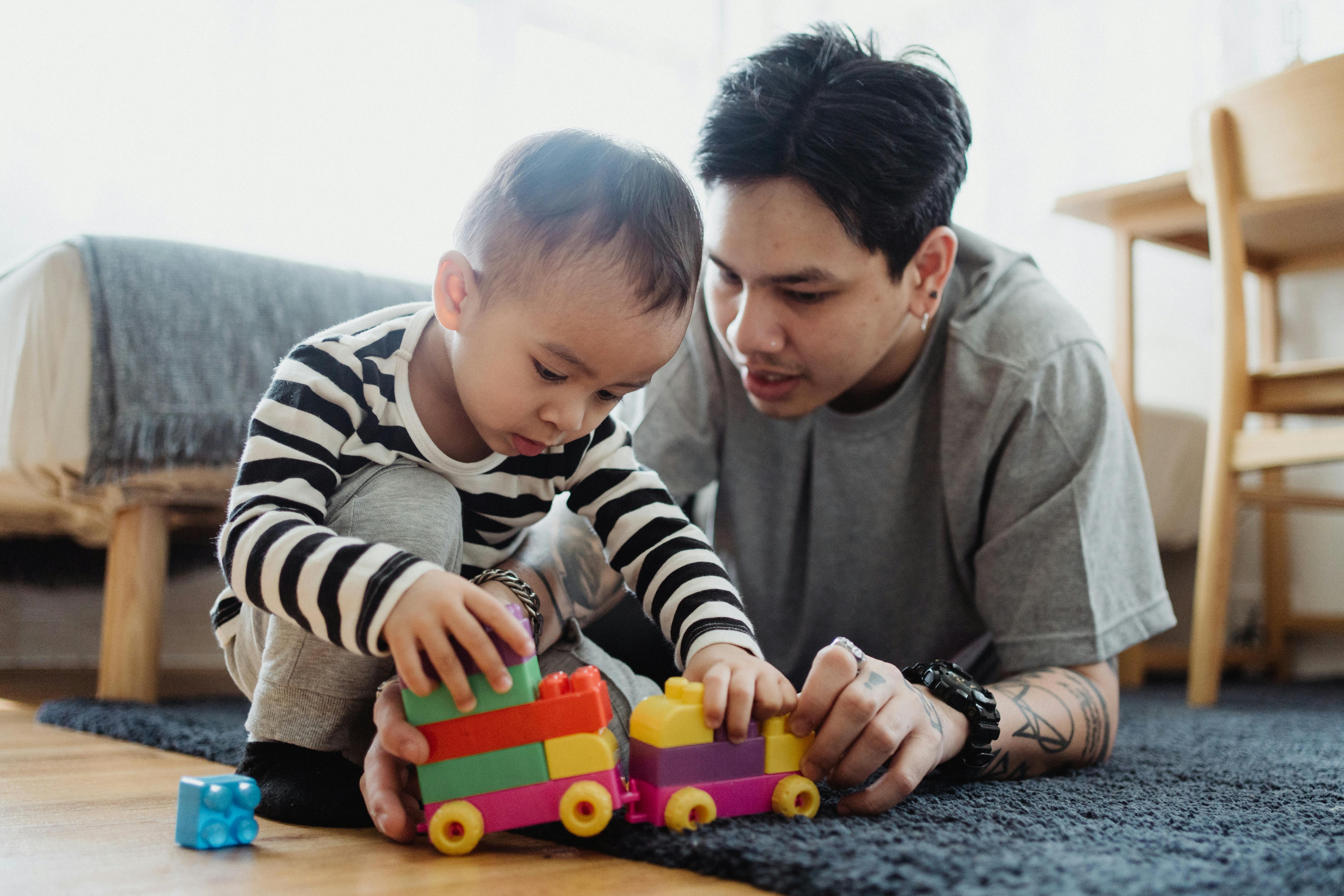 low angle view of man playing with toys with a baby boy on carpet