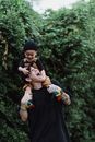 Man in Black Shirt Carrying Baby in White Onesie