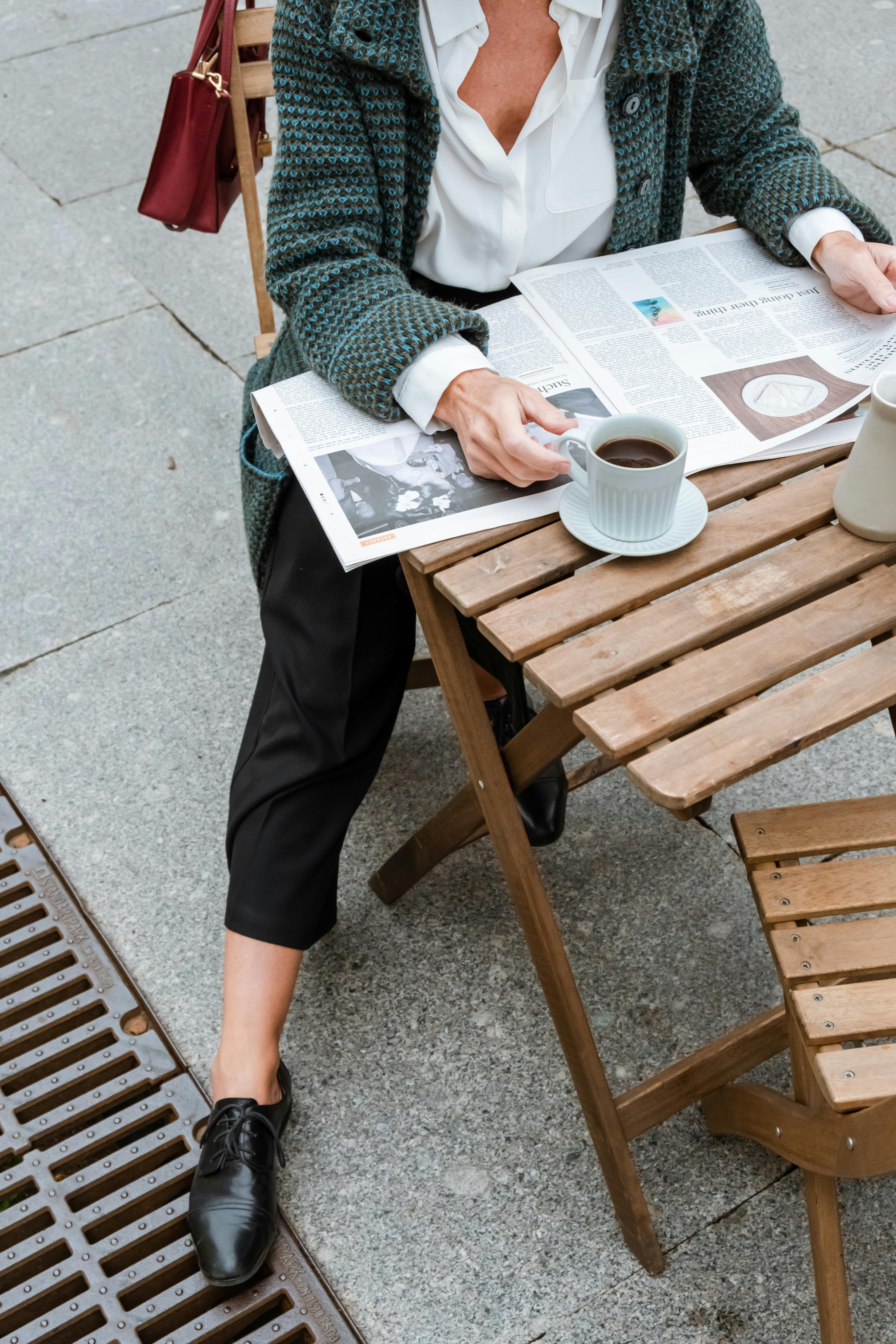 优雅的女人夏天在户外咖啡馆边喝咖啡边看报纸