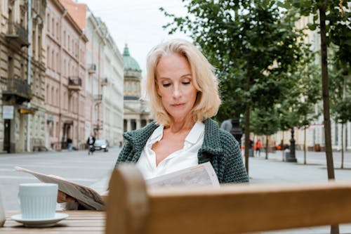 Femeie matură citind la terasă urbană