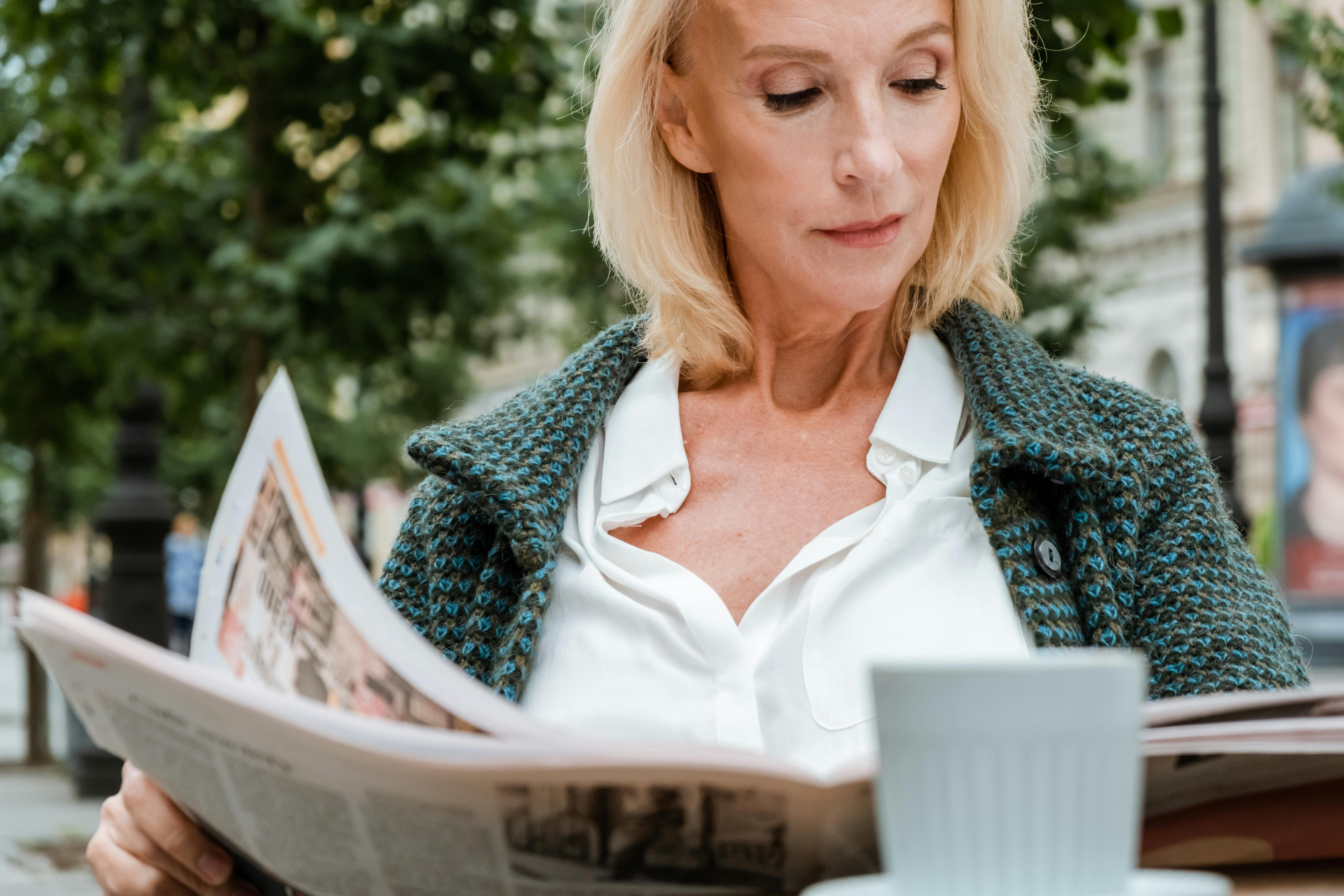 woman in white v neck shirt and gray cardigan reading book