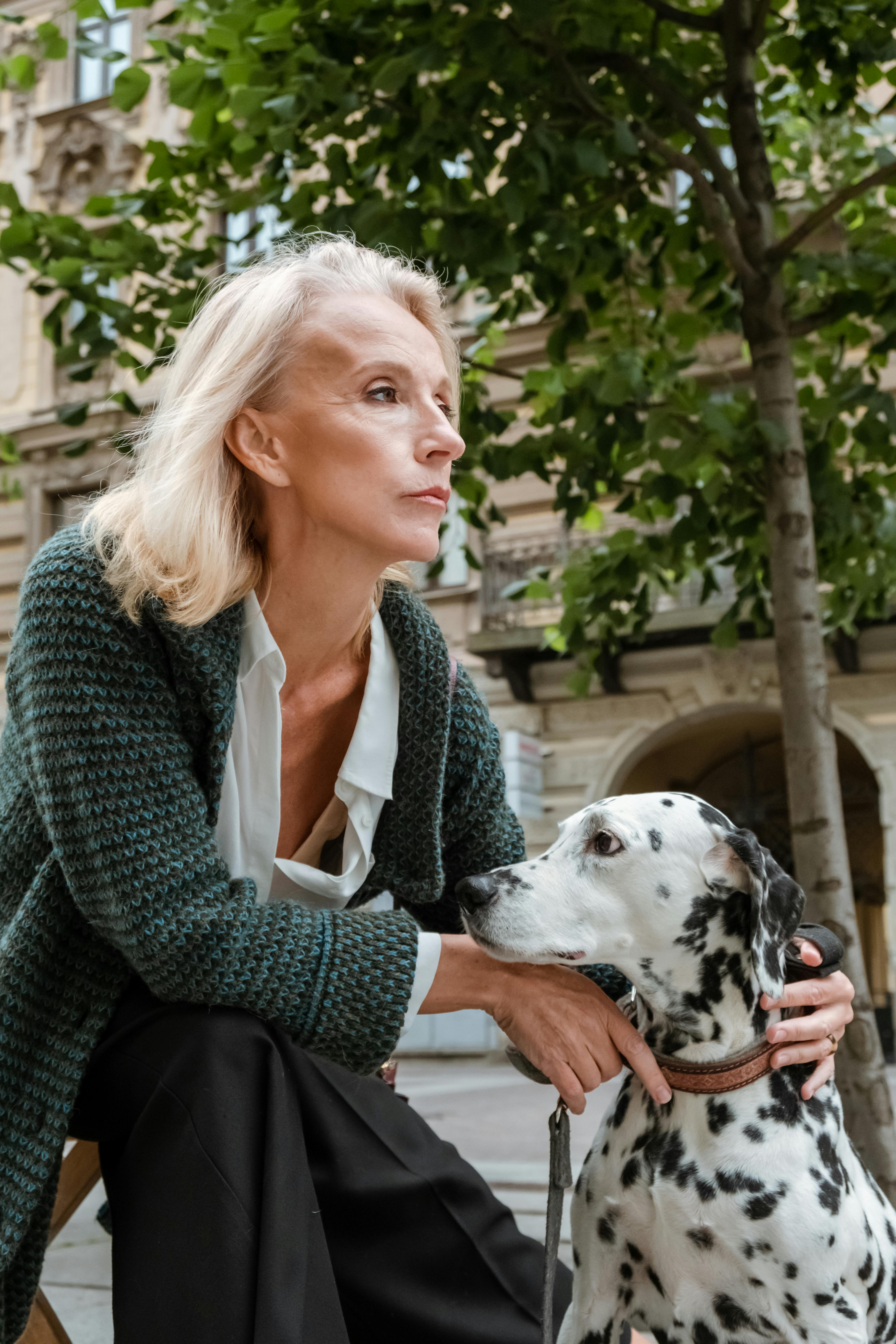 woman in gray cardigan beside dalmatian dog