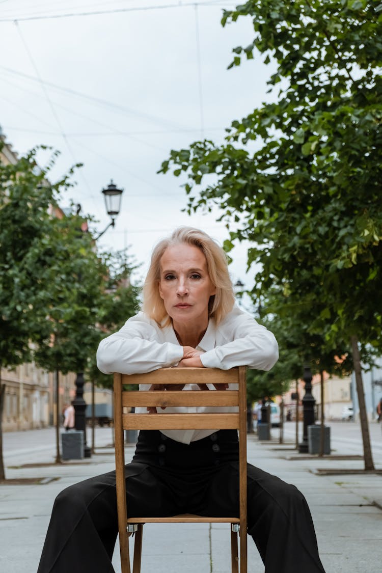 Woman In White Long Sleeve Shirt Sitting On Brown Wooden Chair