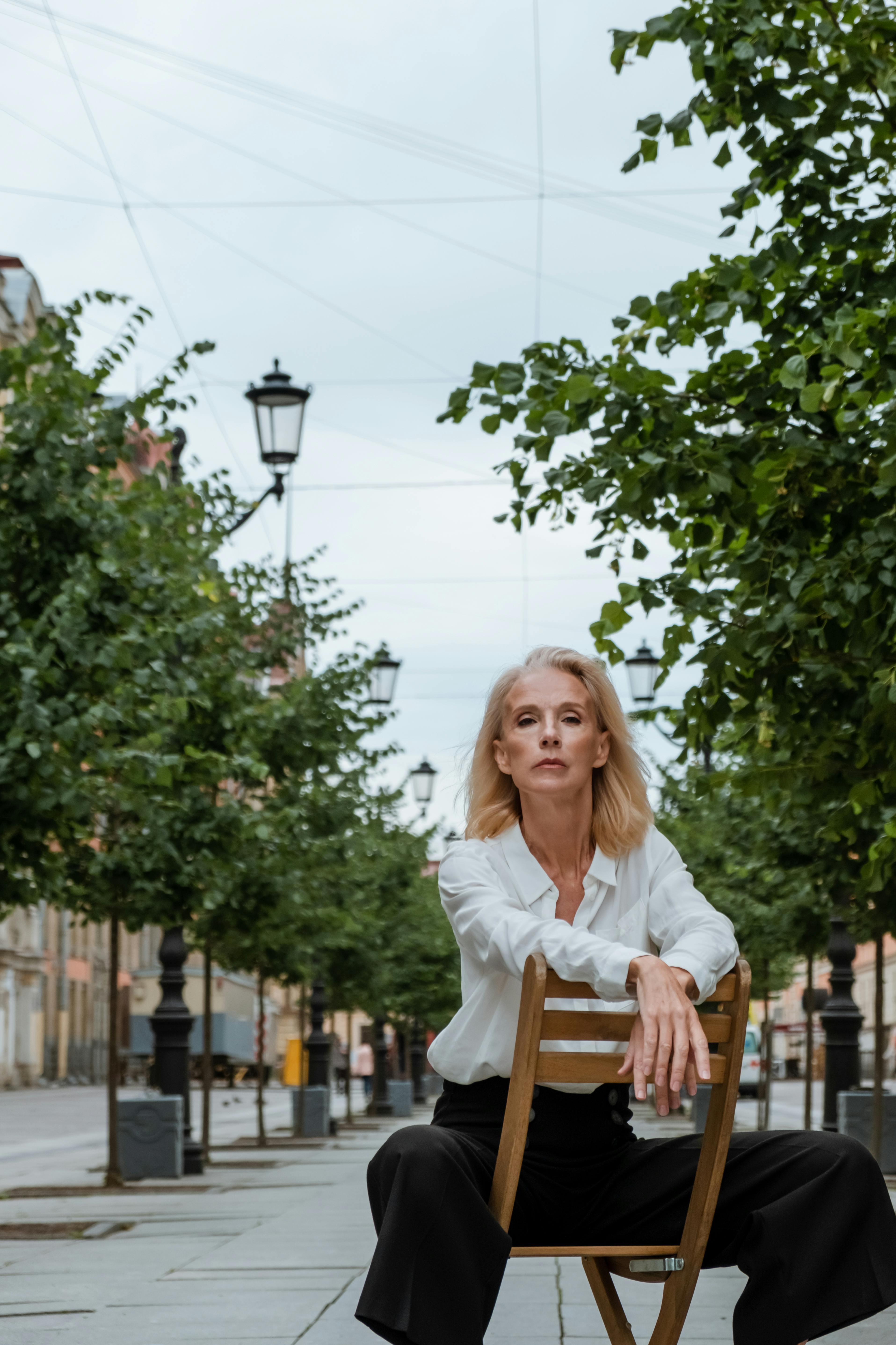 woman in white long sleeve shirt sitting on brown wooden chair