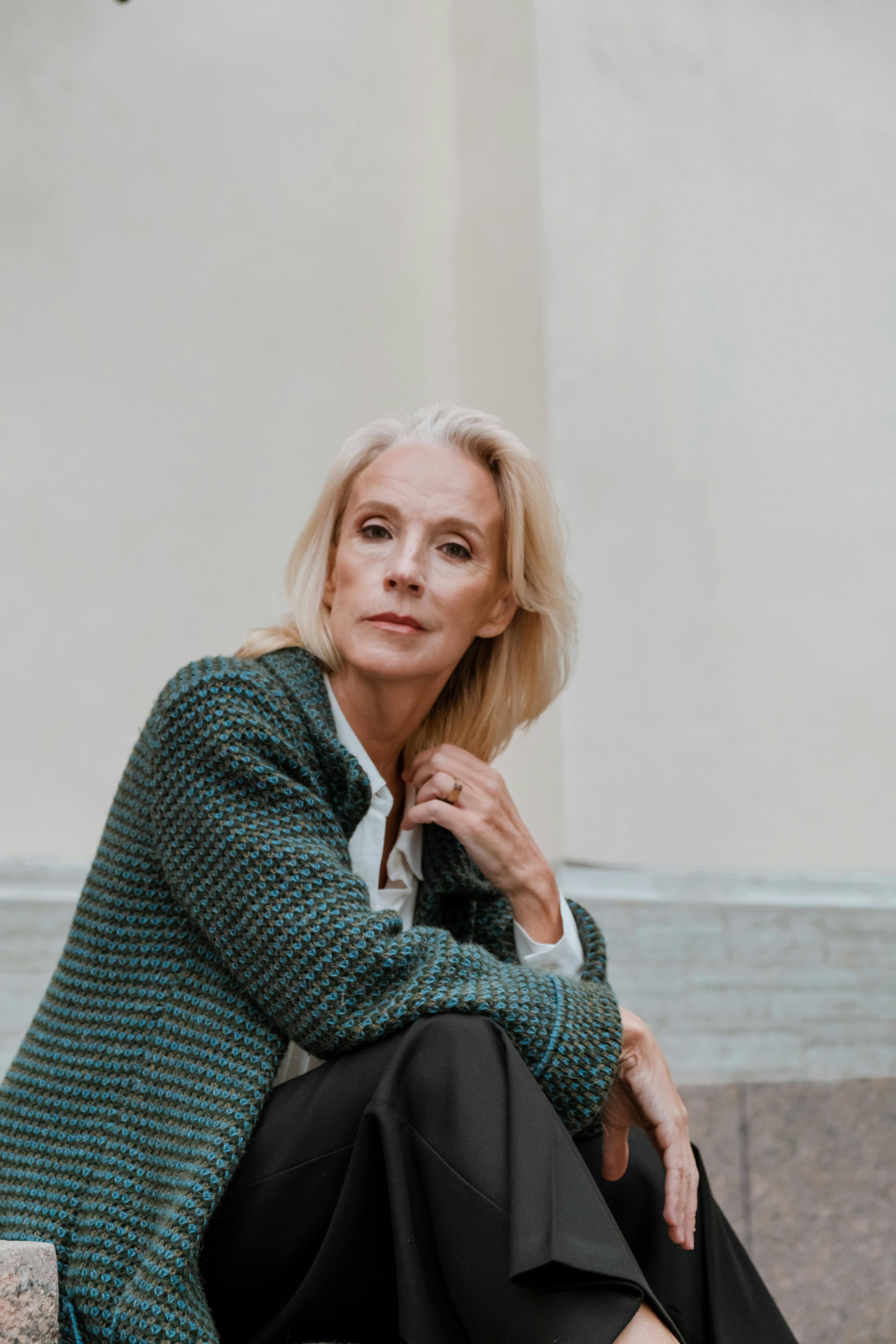 woman in gray sweater sitting on brown wooden bench