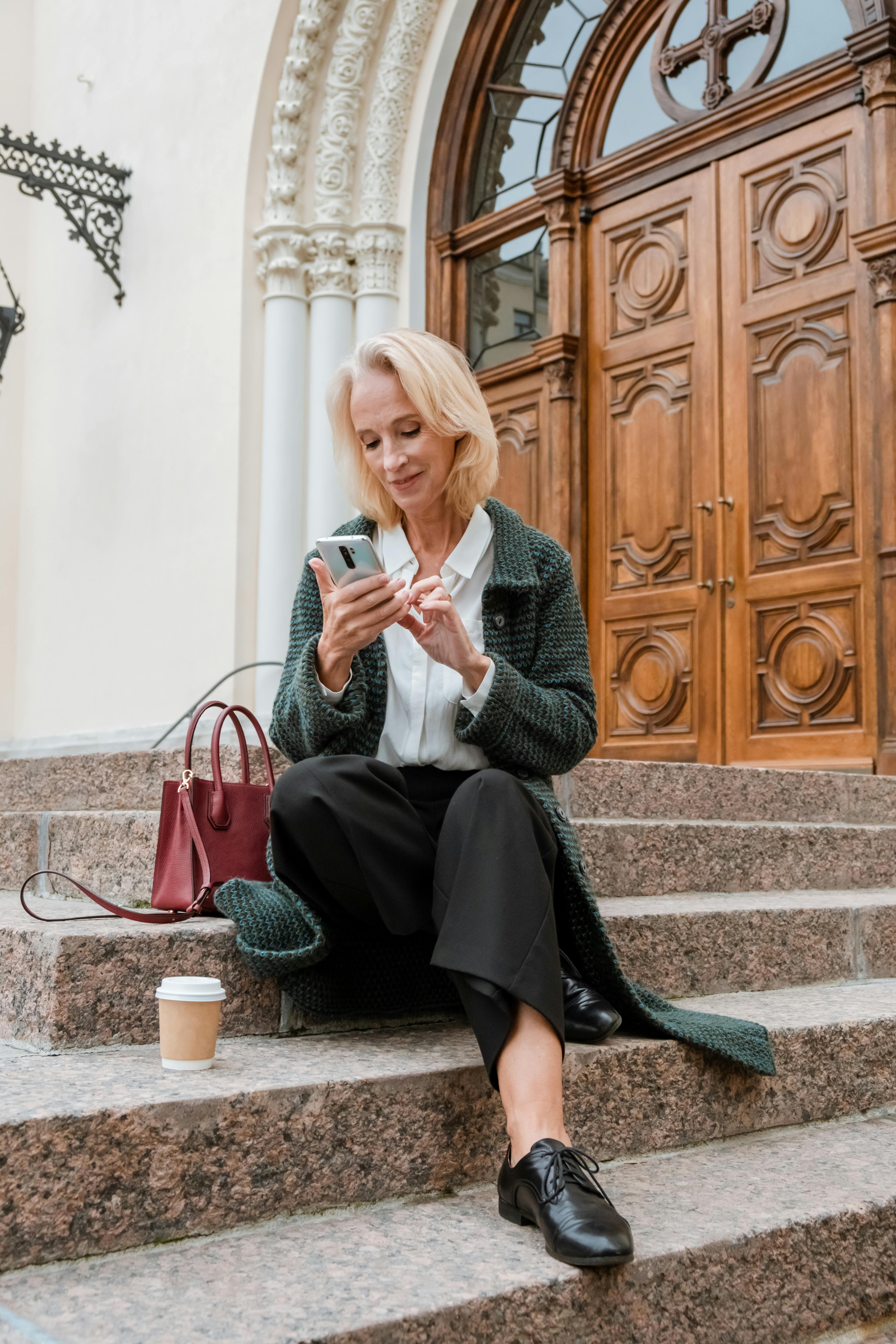 woman in gray coat sitting on brown wooden bench