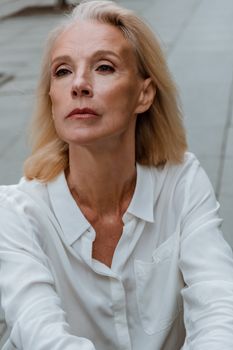 一位身穿白衬衫的成熟女性，在户外显得很自信