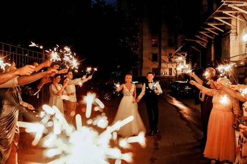 Anonymous friends with sparklers having fun with newlywed couple