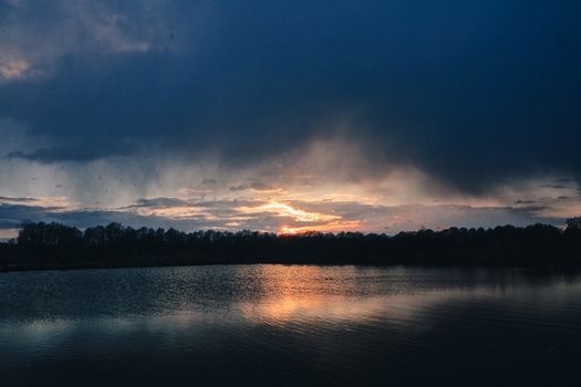 Peaceful twilight scene over a calm lake with trees and reflective water.
