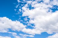 低角度下，白天五彩斑斓的天空、云朵与一只翱翔的小鸟