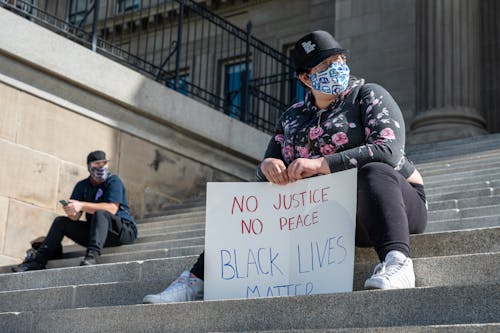 Free Unrecognizable woman with BLM placard resting on stairs in city Stock Photo