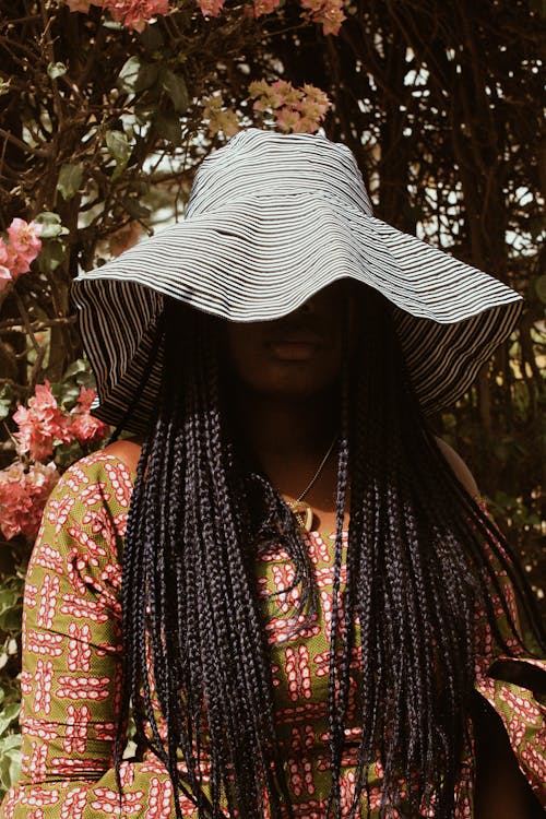 Faceless black woman in hat in garden