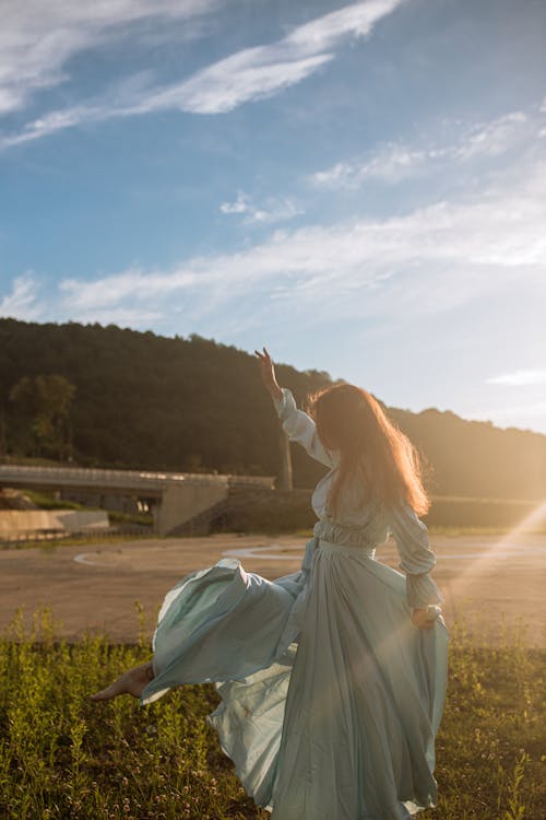 Woman in Blue Dress Dancing on Green Grass