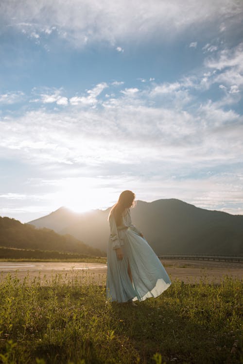 Woman in Blue Dress Standing on Green Grass 