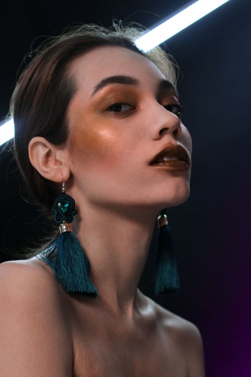 Free Elegant portrait of a woman with striking makeup and bold earrings in a studio setting. Stock Photo